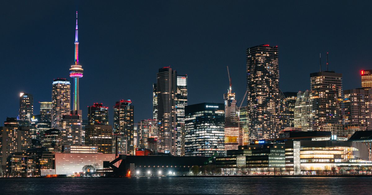 Vibrant night view of Toronto skyline featuring the illuminated CN Tower reflecting on the water.