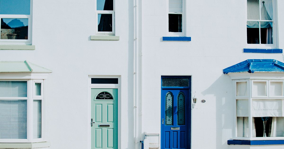 A modern exterior featuring a contrast of blue and green doors on a white building facade.