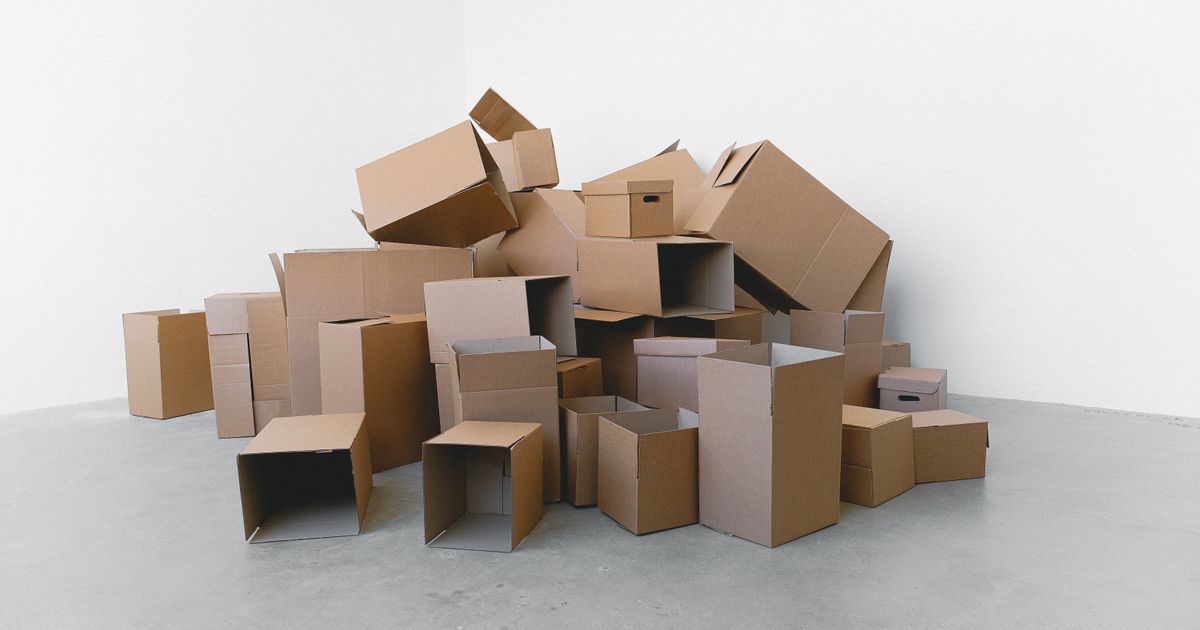 Pile of cardboard containers prepared for relocation on floor at home in daylight on white background